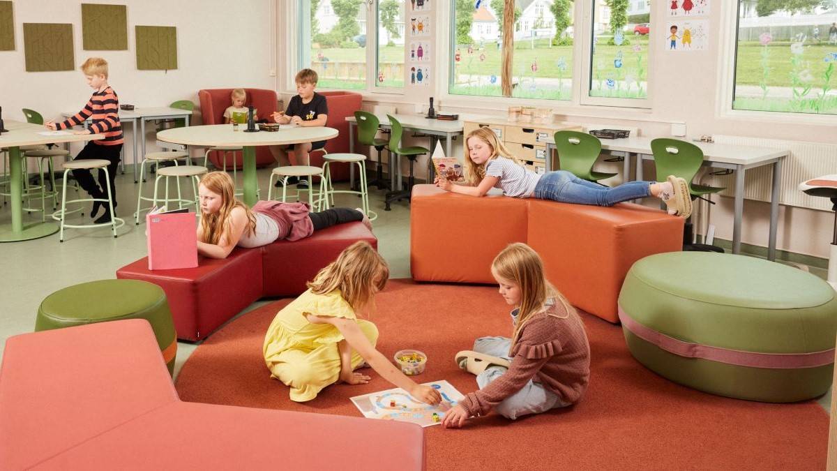Flere barn som gjør aktiviteter i ett rom med fargerike møbler