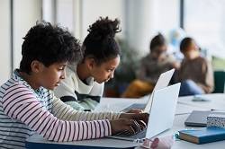 To barn jobber på hver sin laptop i et klasserom. Illustrasjonsfoto: IstockPhoto 