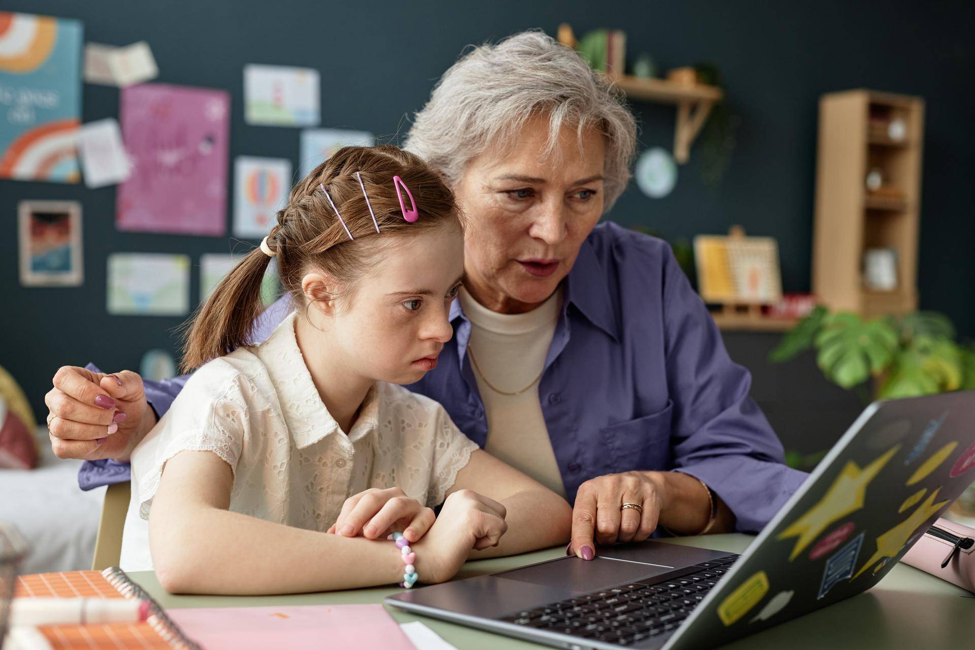 Eldre dame og ung jente med utviklingshemming jobber sammen på en laptop. Illustrasjonsfoto: SeventyFour/IstockPhoto